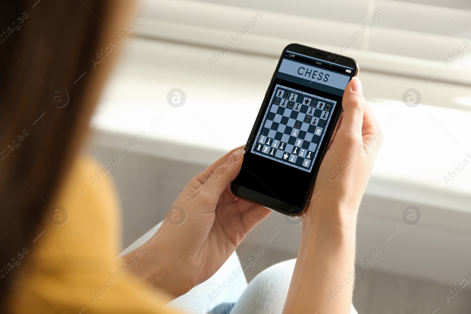 Image of Woman playing online chess on smartphone indoors, closeup