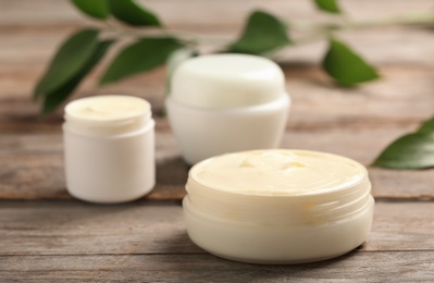 Photo of Closeup view of hand cream jars on wooden background