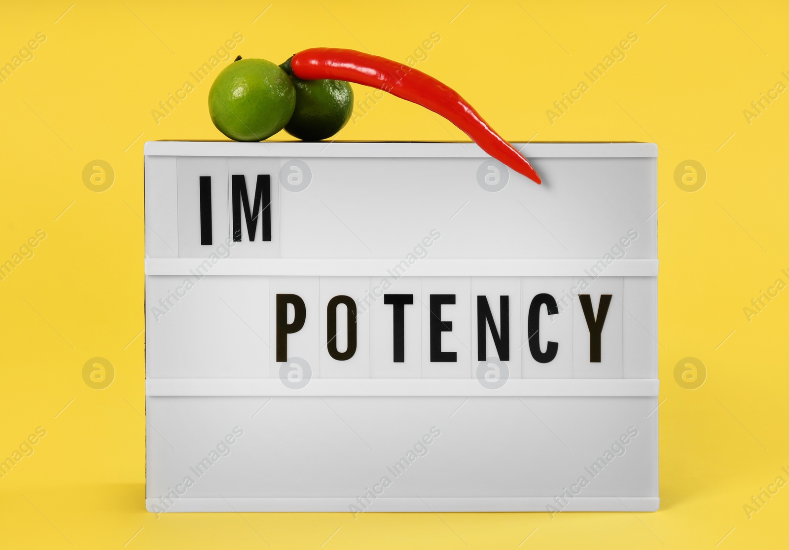 Photo of Lightbox with word IMPOTENCY and products symbolizing male sexual organ on yellow background