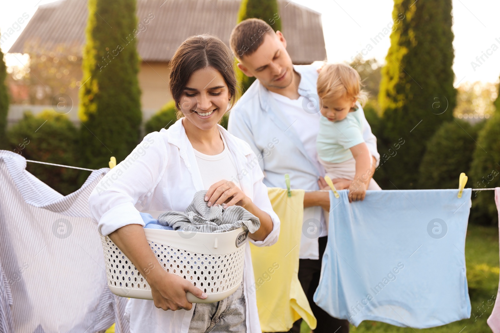 Photo of Happy family near washing line with drying clothes in backyard