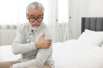 Photo of Arthritis symptoms. Man suffering from pain in shoulder on bed at home
