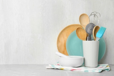 Different kitchen utensils on grey table against light background. Space for text