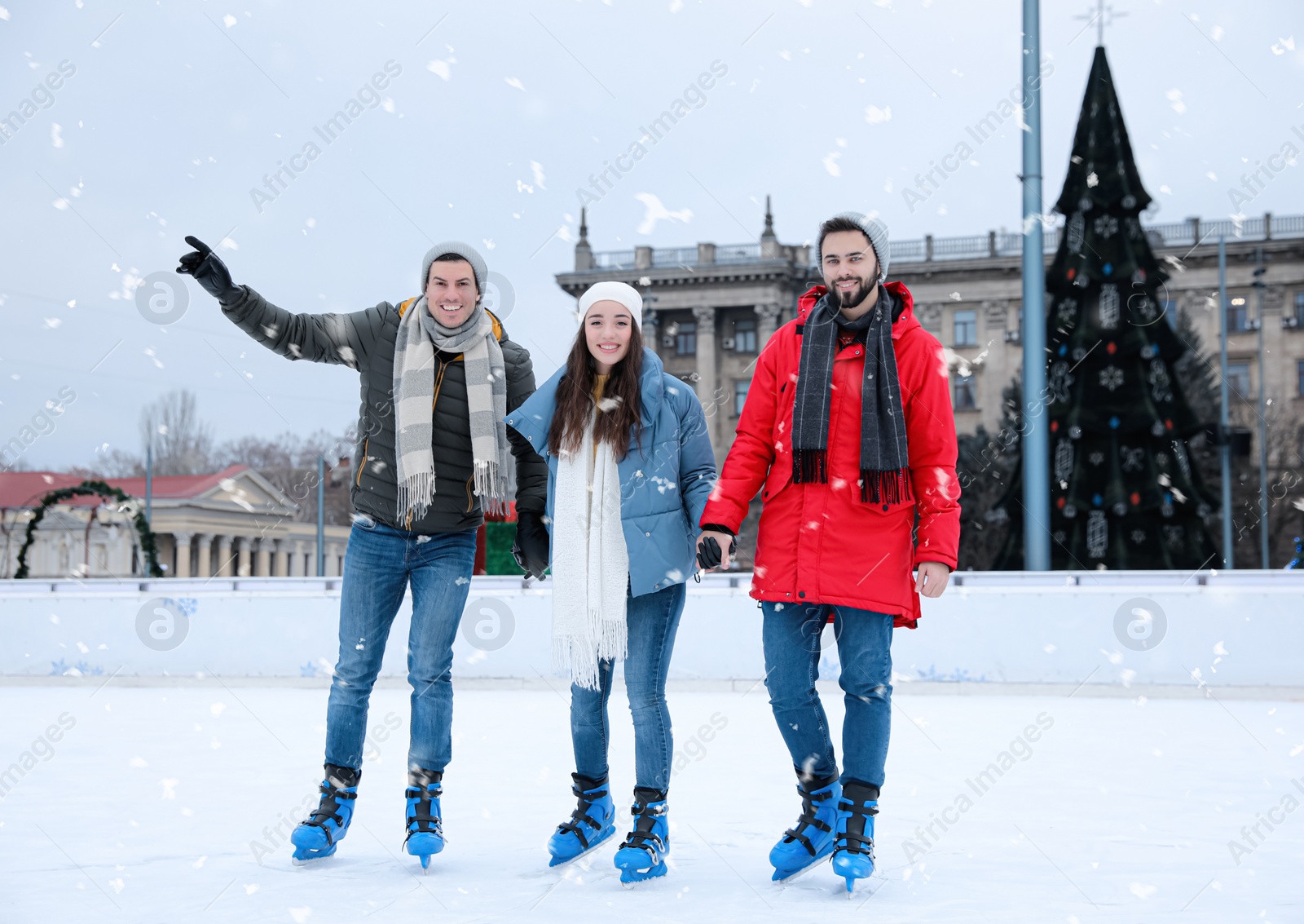 Image of Happy friends skating along ice rink outdoors