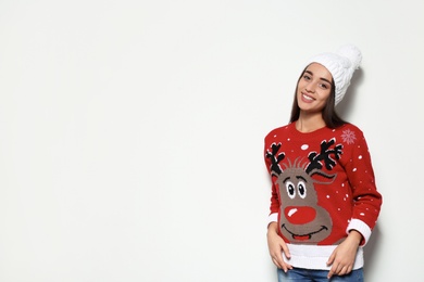 Photo of Young woman in Christmas sweater and knitted hat on white background. Space for text