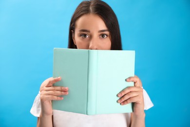 Photo of Beautiful young woman reading book on light blue background