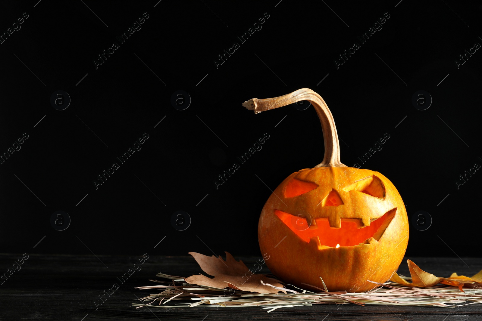 Photo of Halloween pumpkin head jack lantern on table against dark background with space for text