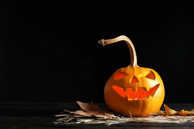 Halloween pumpkin head jack lantern on table against dark background with space for text