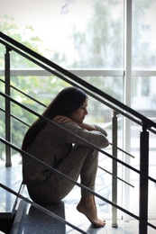 Photo of Depressed young woman sitting on stairs