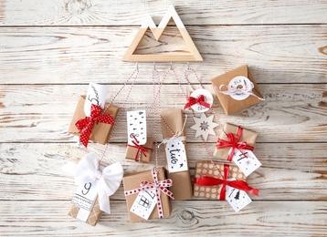 Photo of Gift boxes hanging on white wooden wall. Christmas advent calendar