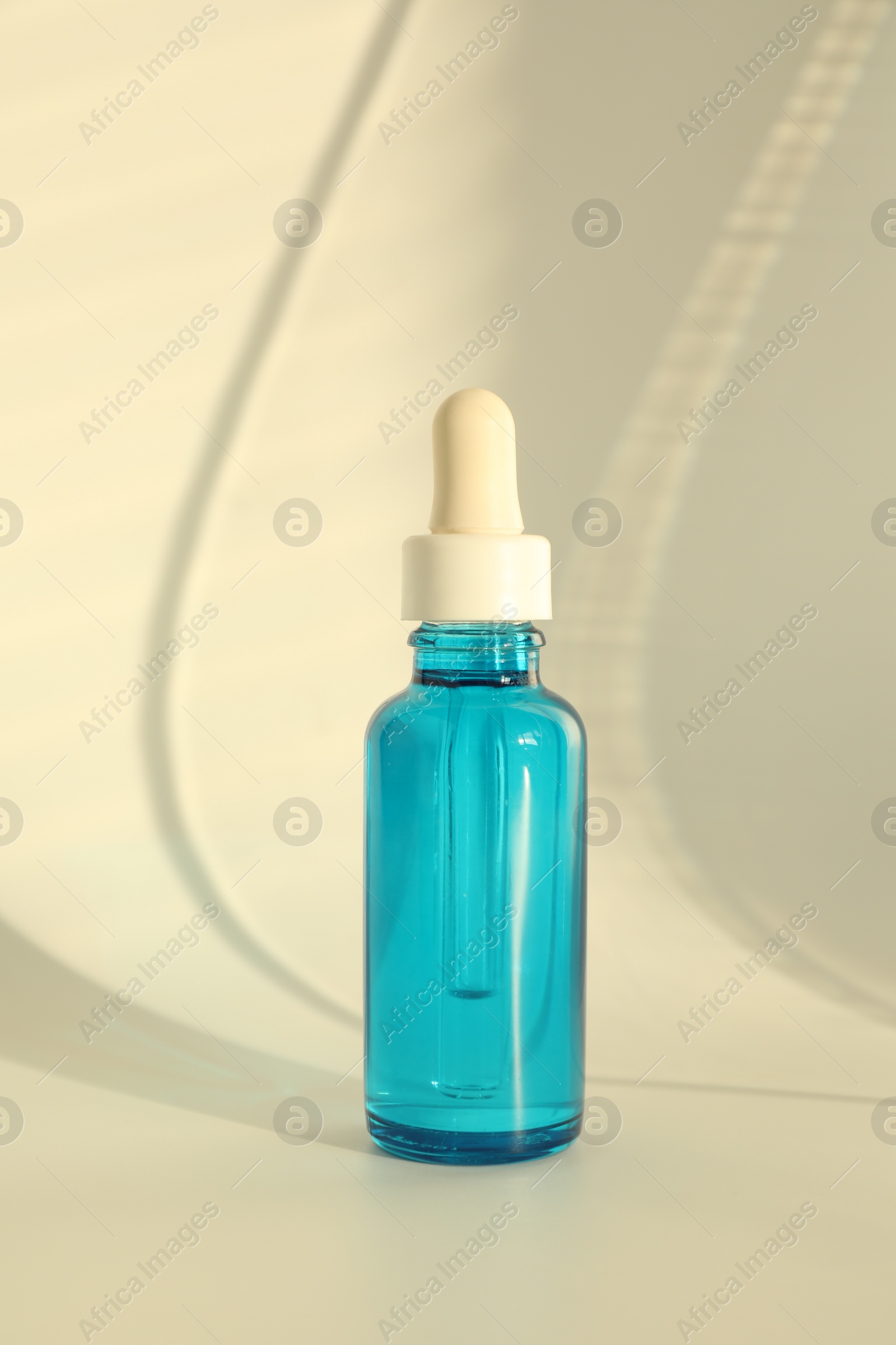 Photo of Bottle with cosmetic product on beige background