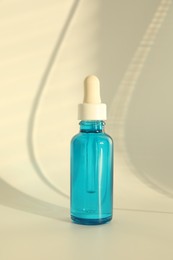 Photo of Bottle with cosmetic product on beige background