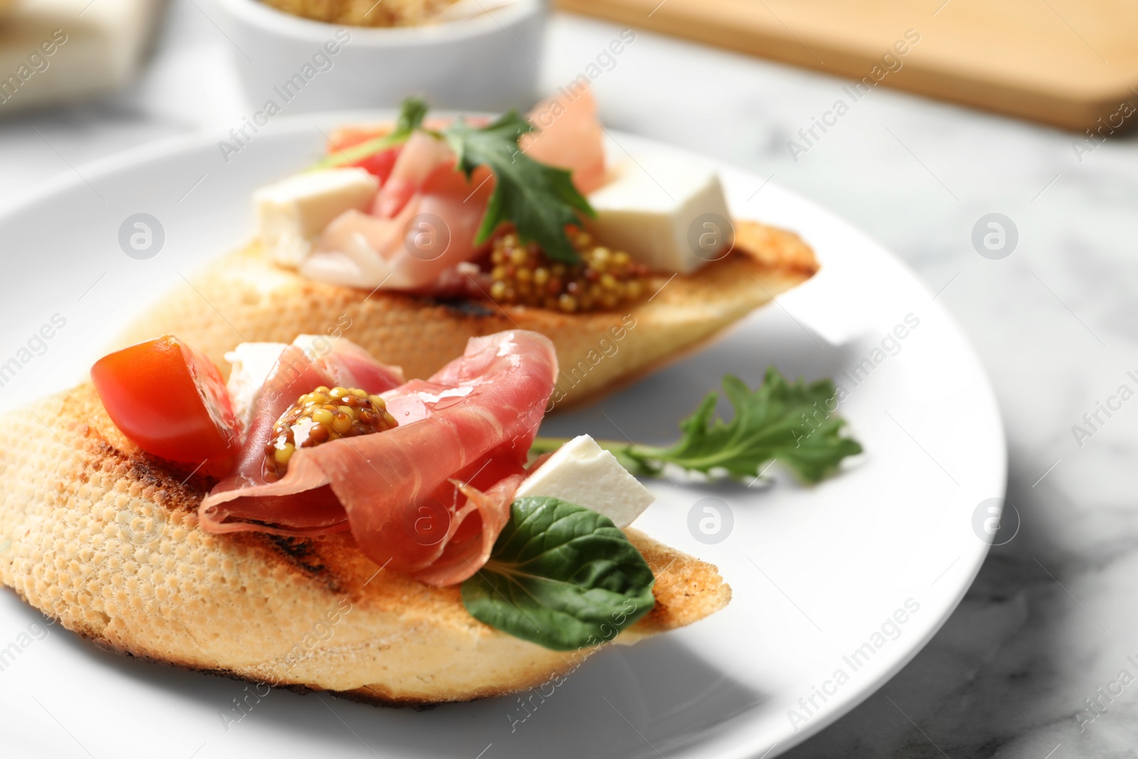 Photo of Plate of tasty bruschettas with prosciutto on table, closeup