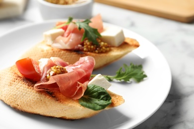 Photo of Plate of tasty bruschettas with prosciutto on table, closeup