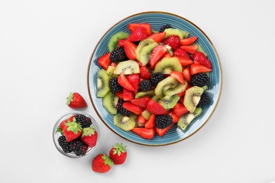 Photo of Plate of fruit salad and ingredients on light background, flat lay