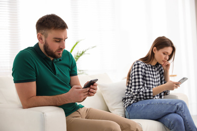 Couple addicted to smartphones ignoring each other at home. Relationship problems