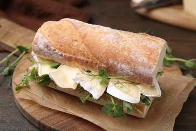 Photo of Tasty sandwich with brie cheese on wooden table, closeup