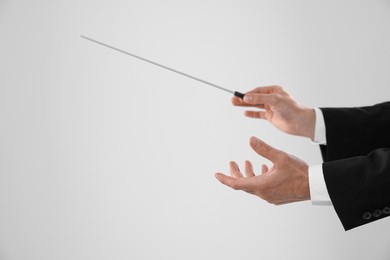 Photo of Professional conductor with baton on light grey background, closeup. Space for text