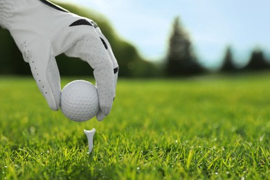Photo of Golfer putting ball on tee at green course, closeup. Space for text