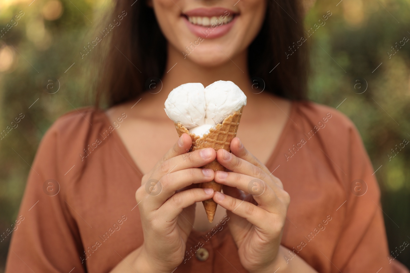 Photo of Young woman with delicious ice cream in waffle cone outdoors, closeup