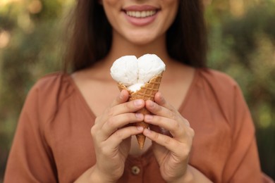 Young woman with delicious ice cream in waffle cone outdoors, closeup