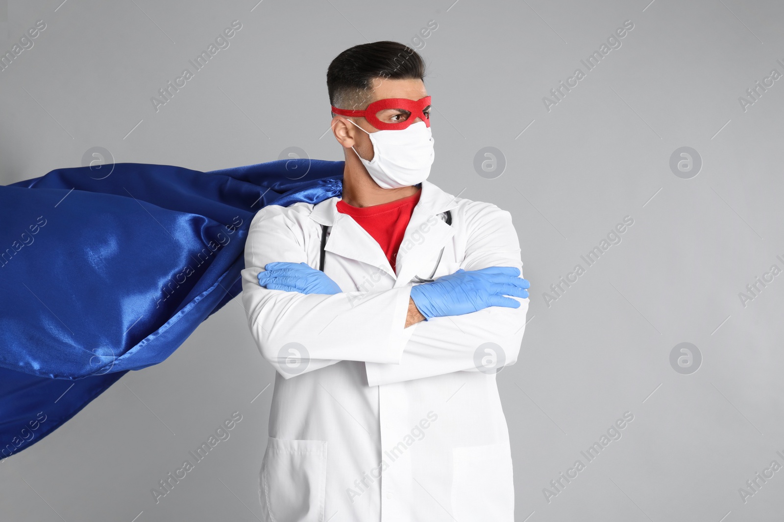 Photo of Doctor wearing face mask and cape on grey background. Super hero power for medicine