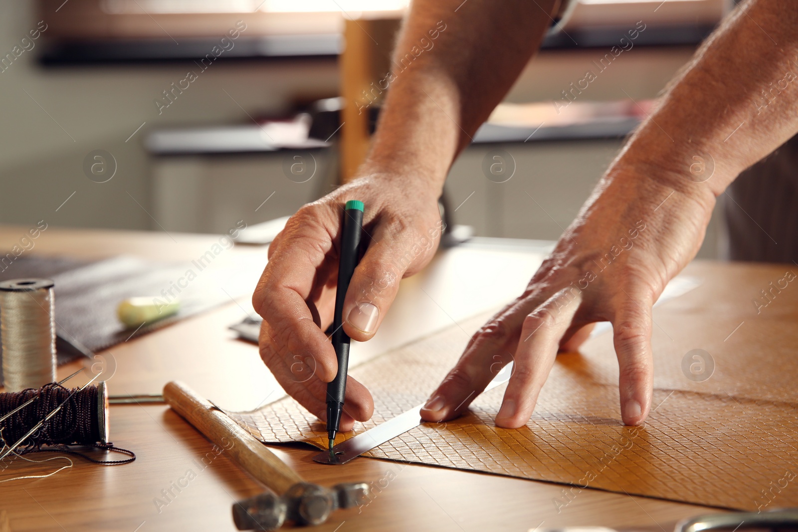 Photo of Man working with piece of leather in workshop, closeup