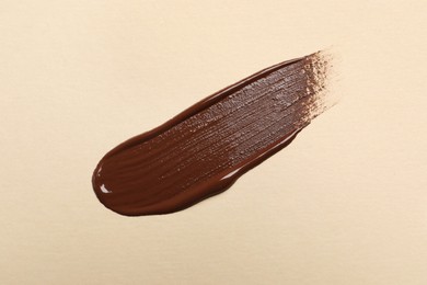 Photo of Smear of skin foundation on beige background, top view