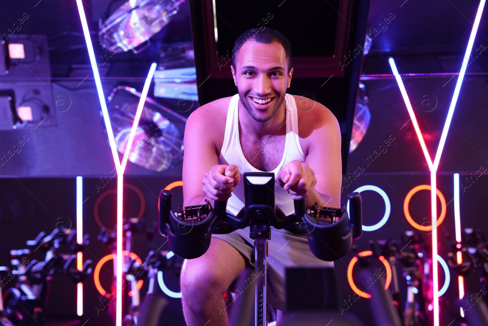 Photo of Young man training on exercise bike in fitness club