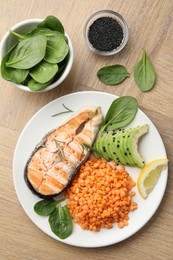 Plate with healthy food high in vegetable fats on wooden table, flat lay