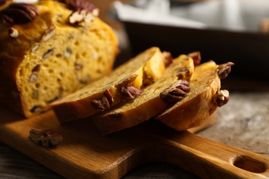 Photo of Cut pumpkin bread with pecan nuts on wooden table, closeup