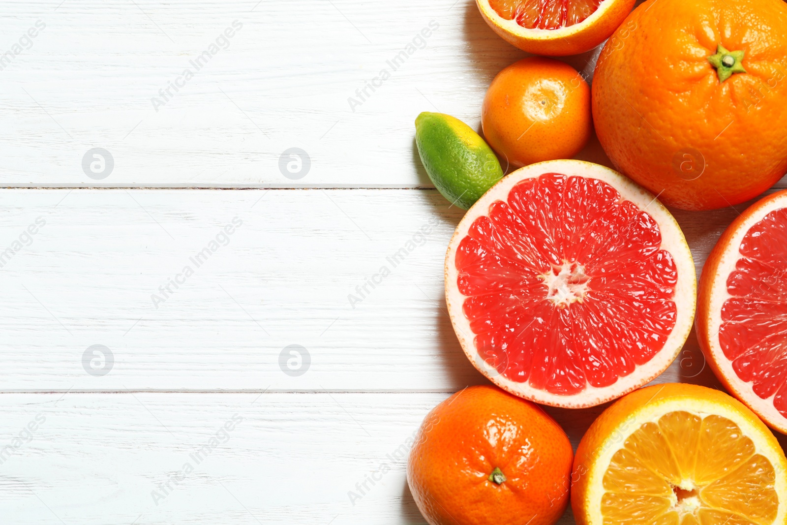 Photo of Flat lay composition with different citrus fruits and space for text on white wooden background