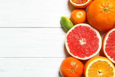 Flat lay composition with different citrus fruits and space for text on white wooden background