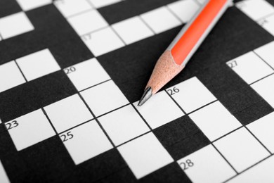 Photo of Pencil on blank crossword, closeup view. Intellectual entertainment
