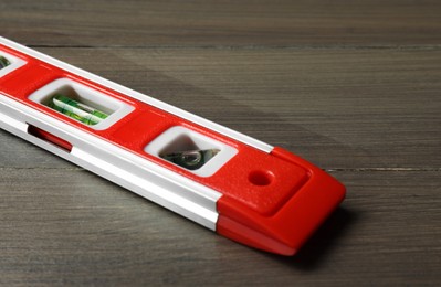 Photo of Red building level on wooden table. Construction tool