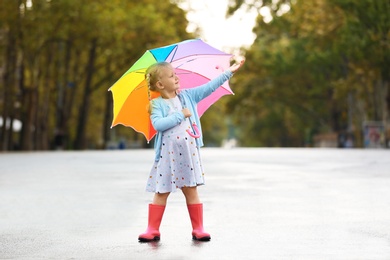 Photo of Cute little girl with bright umbrella on street