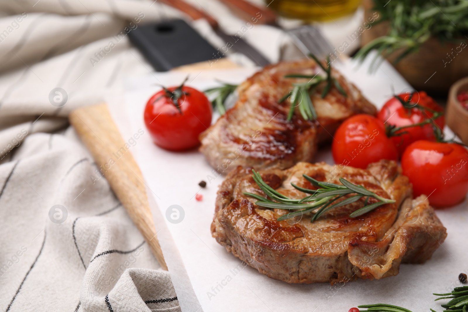 Photo of Delicious fried meat with rosemary and tomatoes on table, closeup. Space for text