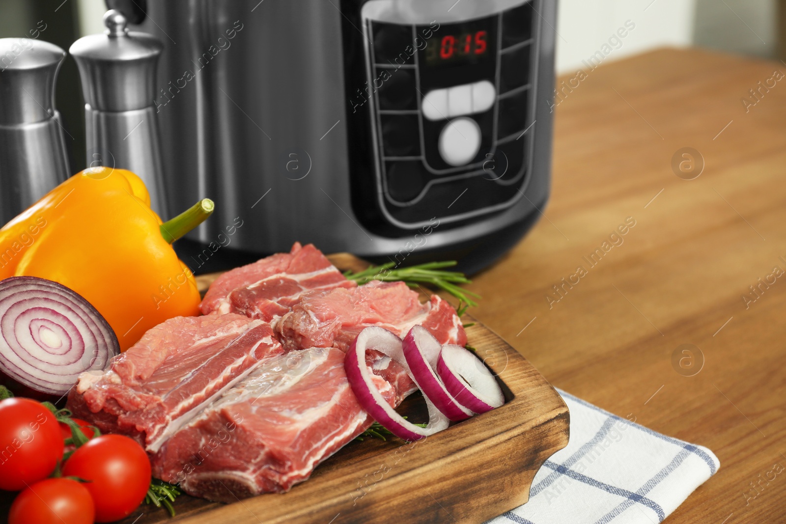 Photo of fresh ingredients and modern multi cooker on wooden table. Space for text