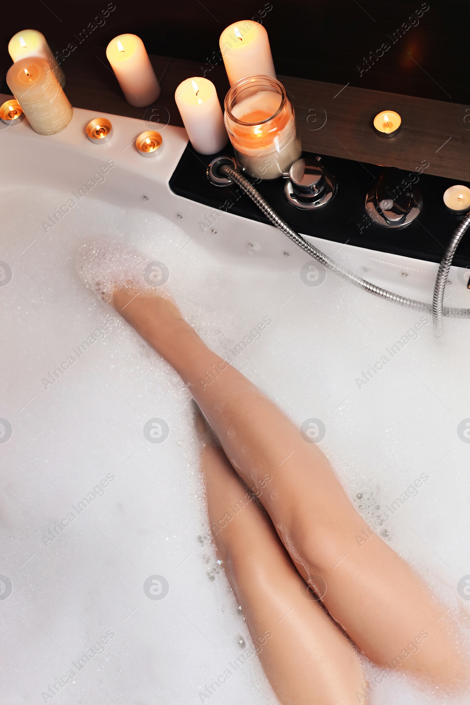 Photo of Woman taking bubble bath, closeup. Romantic atmosphere