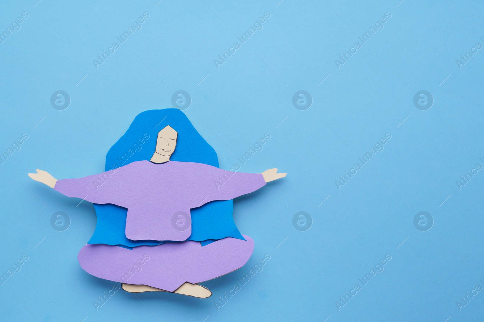 Photo of Woman paper figure on light blue background, top view. Space for text