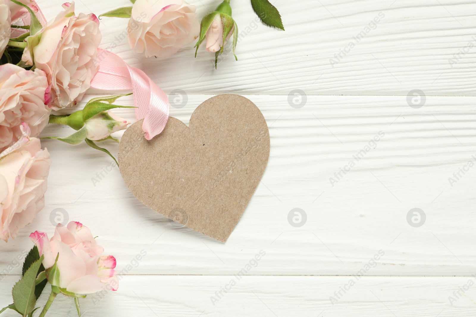 Photo of Happy Mother's Day. Beautiful flowers with blank heart shaped card on white wooden table, flat lay. Space for text