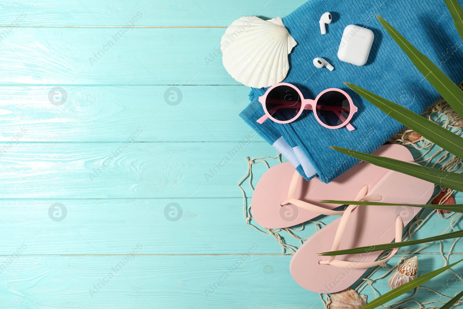 Photo of Flat lay composition with earbuds and beach objects on light blue wooden background. Space for text