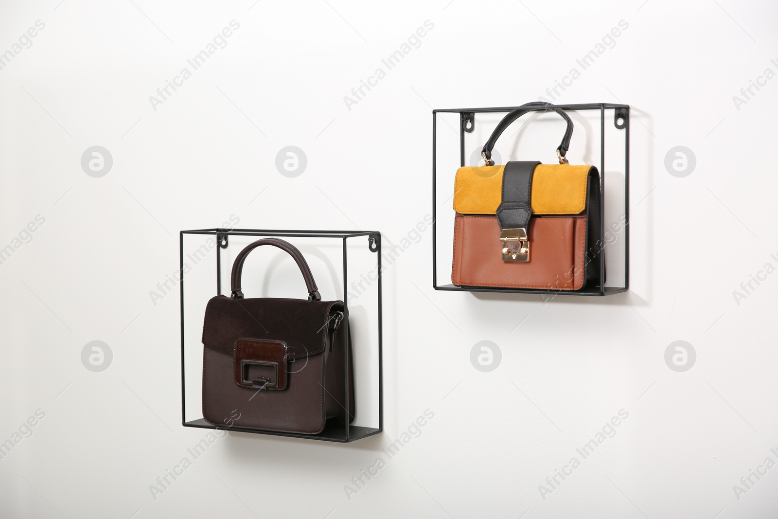 Photo of Metal shelves with stylish woman's bags on white wall