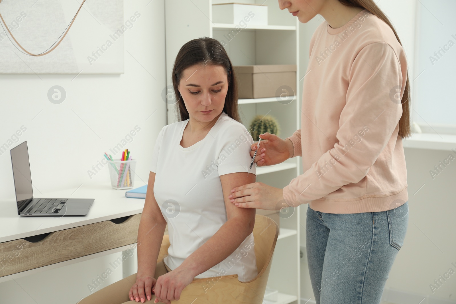 Photo of Woman giving insulin injection to her diabetic friend at home