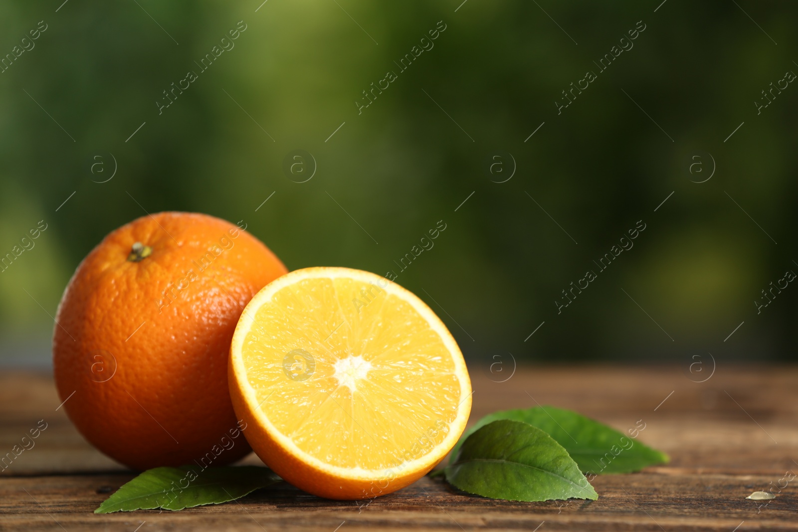 Photo of Fresh ripe oranges on wooden table against blurred background. Space for text