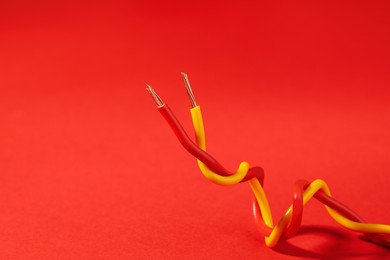 Photo of Two different electrical wires on red background. Space for text