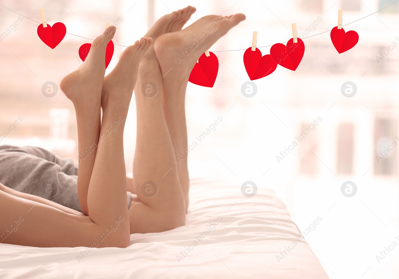 Image of Young couple lying on bed at home and rope with cute red hearts