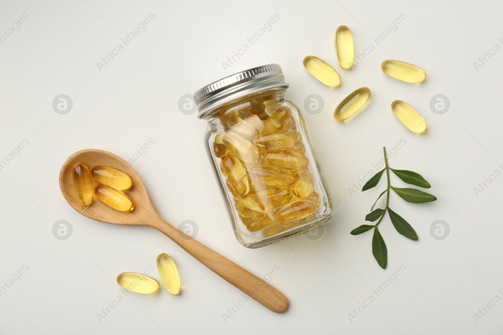 Photo of Bottle, vitamin capsules, spoon and leaves on white background, flat lay