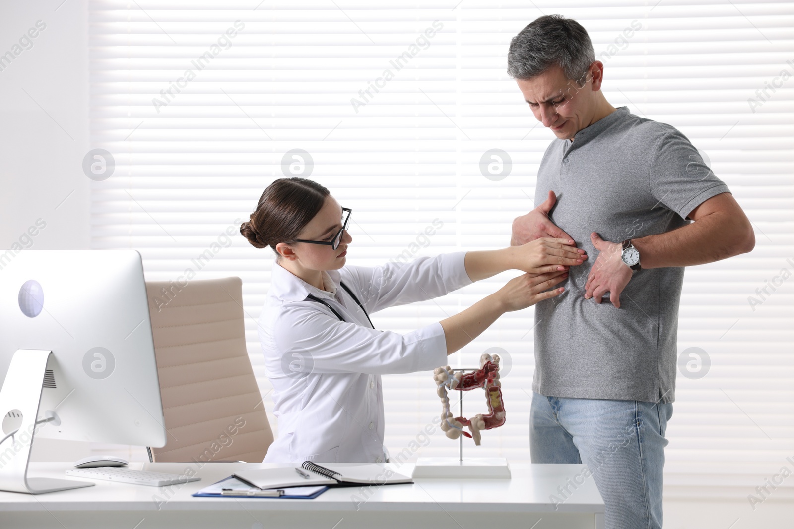 Photo of Gastroenterologist examining patient with stomach pain in clinic