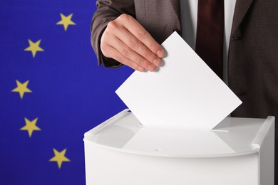 Image of Man putting his vote into ballot box against flag of Europe, closeup. Space for text