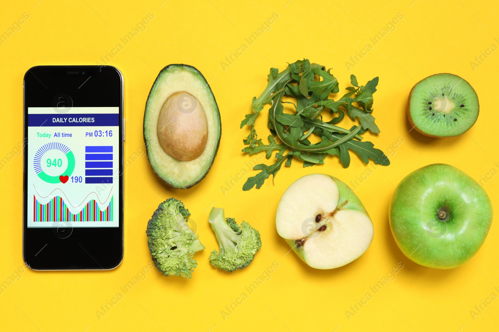 Photo of Smartphone with weight loss calculator application and different products on yellow background, flat lay